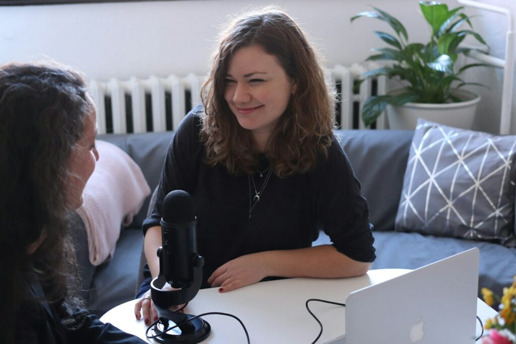 woman in black half-sleeved shirt sitting while facing woman and smiling